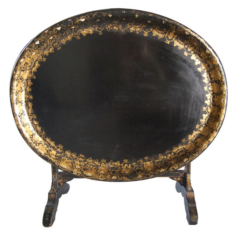 Black oval wood lacquered tray with gold foliate border decoration on a (later) stand painted with a gold filet on black. Table measures 30
