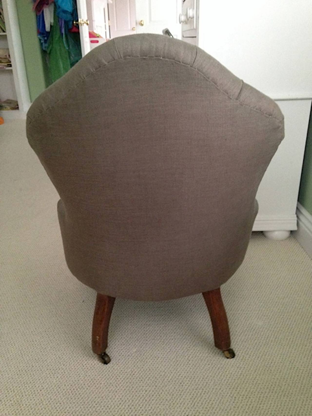 A nursing chair or low fireside chair newly upholstered in taupe Belgian linen with tufted back, turned front legs, saber back legs. The seat height is 11