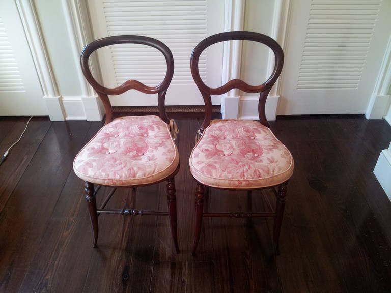 Pair of mahogany balloon back chairs with turned legs and stretchers. The seats are upholstered in Bennison linen fabric with an overlaying squab cushion. Seat height without cushion is 17.5