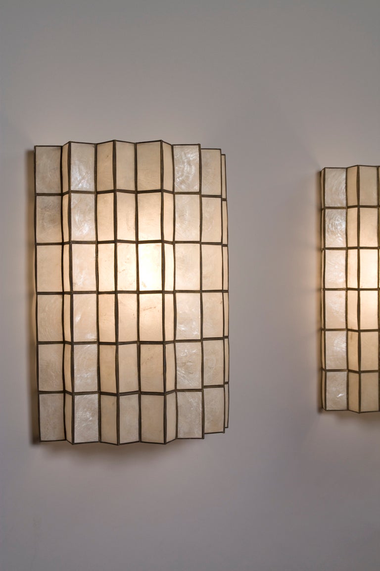 Pair of capiz shell sconces, of semi-circular shape with sawtooth edge, the shell pieces set in a brass grid, American 1960s. Width 11 3/8 in, height 15 in, depth 6 in. (Item #1674)