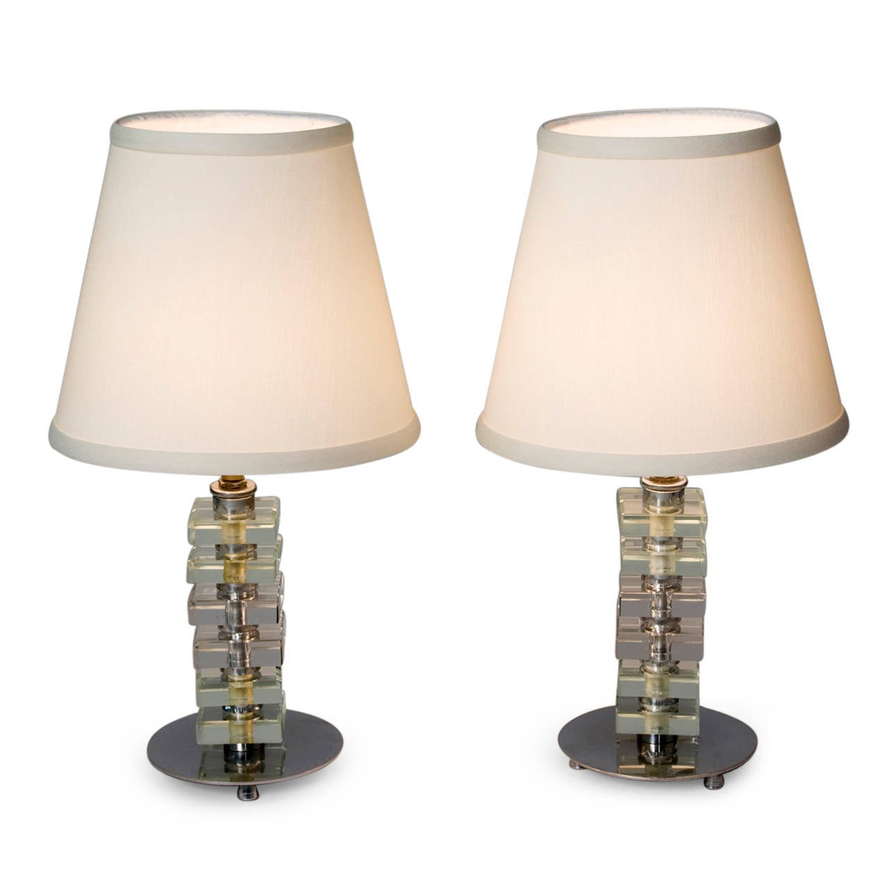 Pair of stacked glass boudoir lamps, the square glass elements separated by nickeled bronze discs, and resting on a larger nickeled bronze base having four feet, in custom silk shades, in the style of Jacques Adnet, French 1930s. Overall height 15