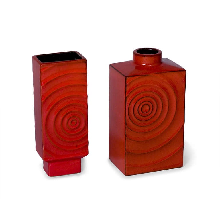 Set of two red glazed ceramic vases, of tall rectangular form with raised concentric circle decoration, 