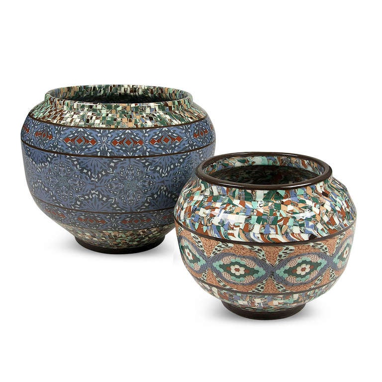 Two vases, sold together or separately. 

On left: Large circular ceramic vase, the form built by ceramic mosaic elements in colors of blue, grey, black, and white, a central blue band over a speckled background, by Atelier Gerbino, Vallauris,