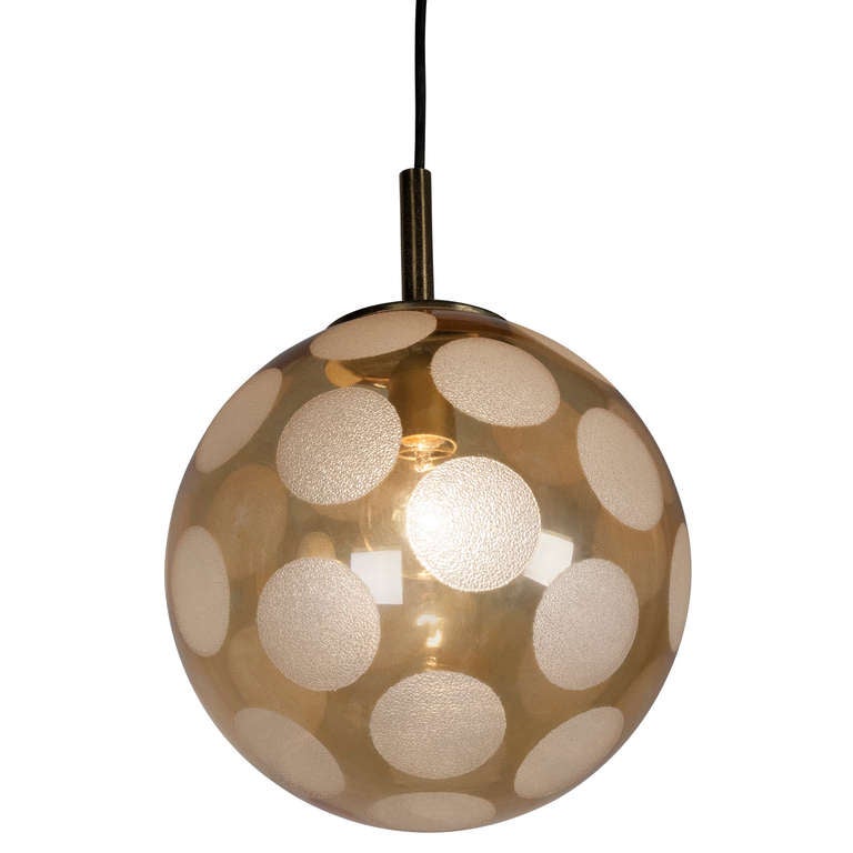 Spherical golden glass chandelier, with a pattern of frosted circles around its surface, suspended by a cord with a cylindrical polypropelene ceiling cup, German 1960s. Diameter of sphere 12 in. (Item #1960)