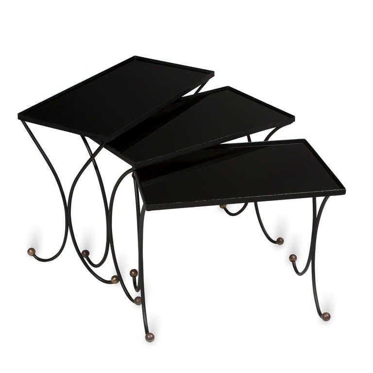 Set of three iron and black glass top nesting tables, curved legs with brass ball feet, French 1950s, in the style of Jean Royere. The largest measures 24 x 12 in, height 18 3/4 in. (Item #2056)
