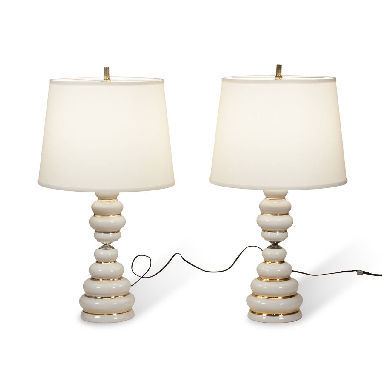 Ceramic table lamps, composed of white glazed stacked disc shapes of varying diameter, with gold glaze in between each, narrow at the center of the column, American 1960s. Overall height 28 in, largest diameter of base 6 1/2 in. Shade measures top