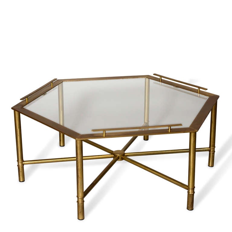 Bronze hexagonal shaped coffee table, with glass top, on six legs having stretchers meeting in center, and three of six sides of hexagon having raised gallery type edge, by Mastercraft, American 1970s. Distance from point to point 42 in, distance