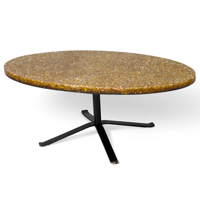 Crackle resin top oval coffee table, the orange resin poured and with small glass cube inclusions, on a black painted stainless steel base, the four legs emanating from a central column. 42 1/2 in x 23 1/2 in, height 16 1/2 in, surface thickness 1