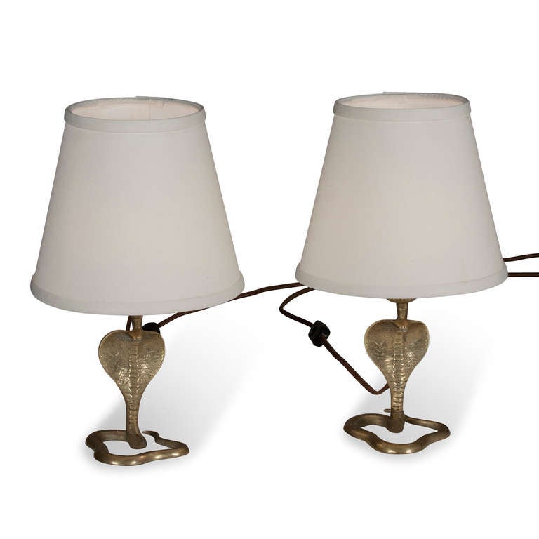 Pair of bronze cobra form tables lamps, the serpent standing with hood open, and body loosely coiled, French 1930s. In custom silk shades. Overall height 14 in, base measures 4 in x 4 1/4 in, shade measures top dia 5 1/2 in, bottom dia 8 1/2 in,