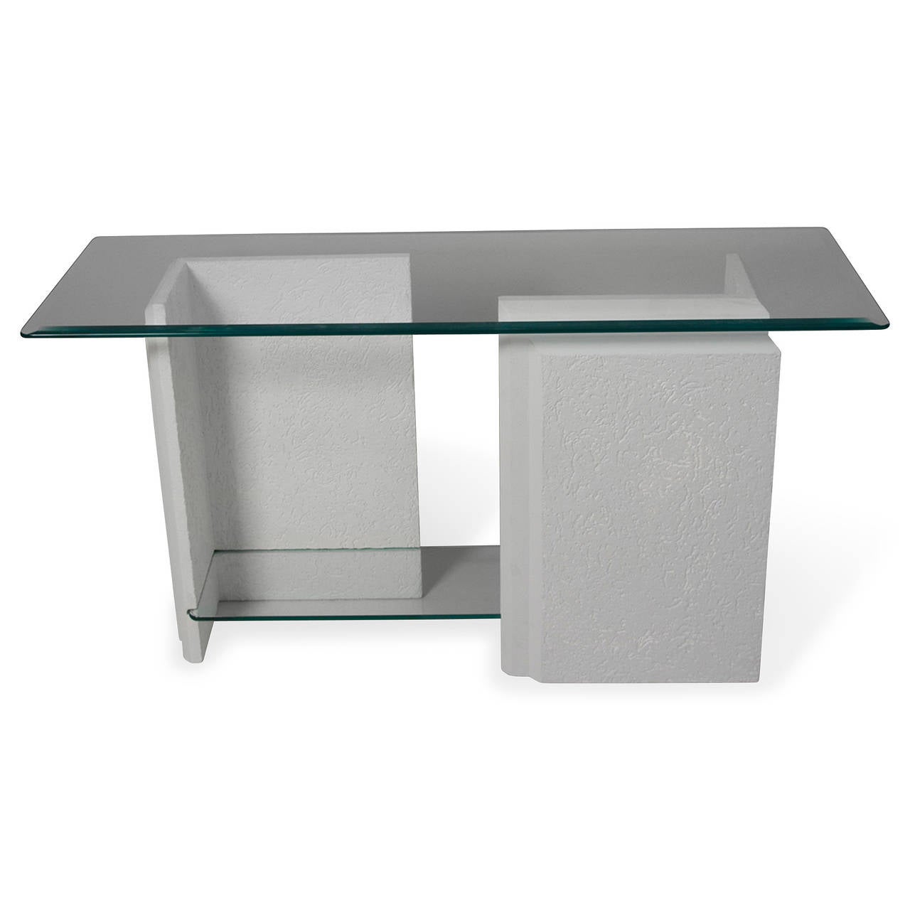 Stone console table, with beveled glass top and lower glass shelf mounted between the two L-shaped stone bases, the bases in a textured white with stepped molding along visible edges. American 1980s. Height 27 in, glass top measures 54 in x 18 in,