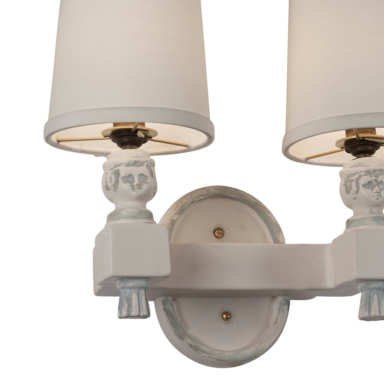 Antiqued ceramic two-arm sconces, the two curved block arms emanating from a center oval backplate, with female head form on each arm, just below custom shades. French 1940s. In the style of André Arbus. Overall dimensions: height 12 in, width 13