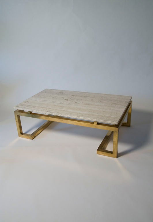 Travertine top brass base rectangular coffee table, the surface resting on a square stock frame shaped in a Greek key manner on either end, while raised on four small brass elements. French circa 1970. 47 1/4