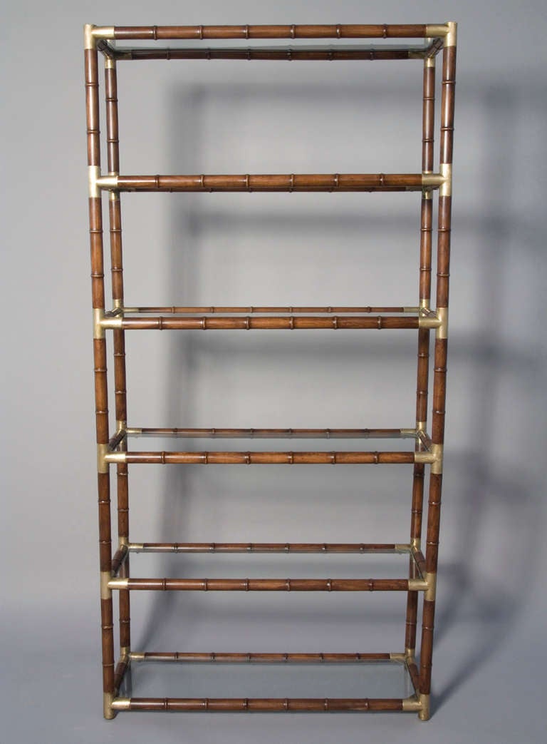 Faux bamboo wood six shelf etagere, with bronze fittings on corners, and glass shelves. In the style of Billy Haines, American circa 1960. Width 35 in, depth 12 in, height 71 in. (Item #1307)