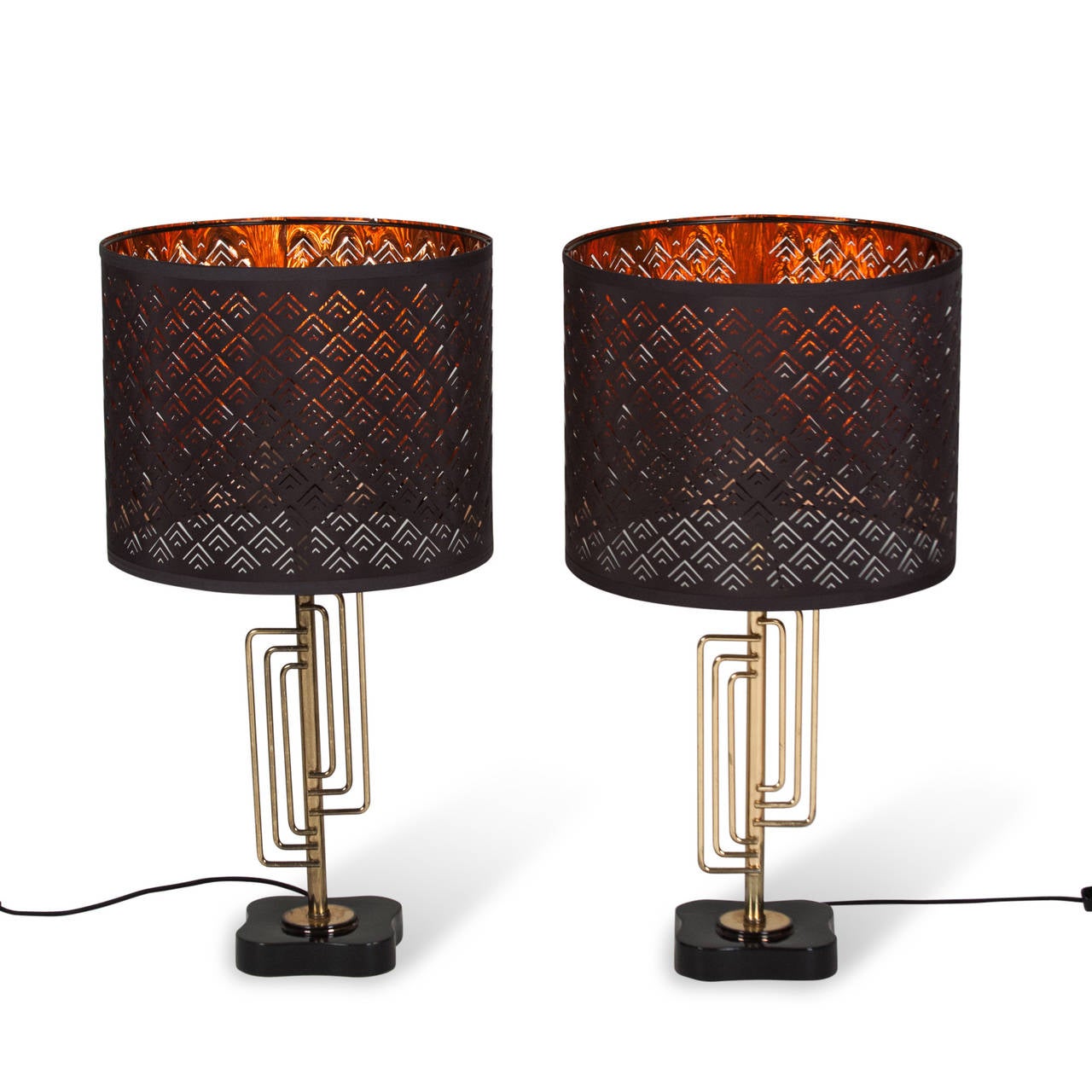 Pair of bent brass rod table lamps, the rods in a concentric geometric shape, post mounted with a black metal base, in black perforated shades with reflective metallic lining, American circa 1960. Overall height 28 in, base measures 6 in across at