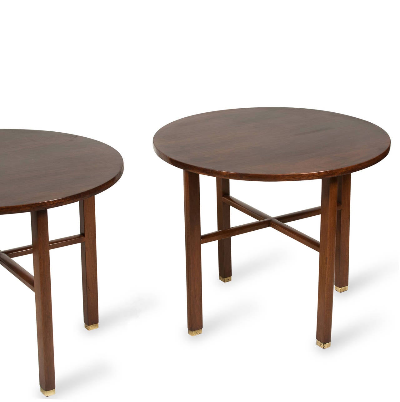 Mahogany occasional or end tables, circular top on four rectangular legs, joined by an X-stretcher, brass cap feet. By Dunbar, American 1950s. Stamped to underside. Height 22 1/2 inches, diameter 27 inches. (Item #2218)