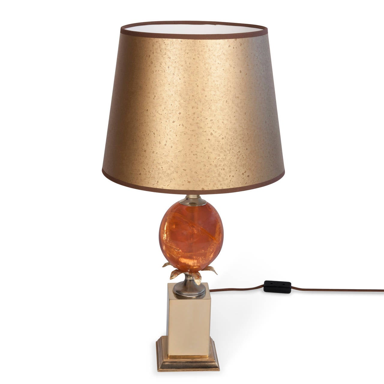 Single fractured resin table lamp, the orange resin in an ovoid shape, resting on a square brass base, French, early 1970s. In custom mottled gold paper shade. Overall height 25 1/2 in. Base measures 5 in square. Shade measures top diameter 10 in,