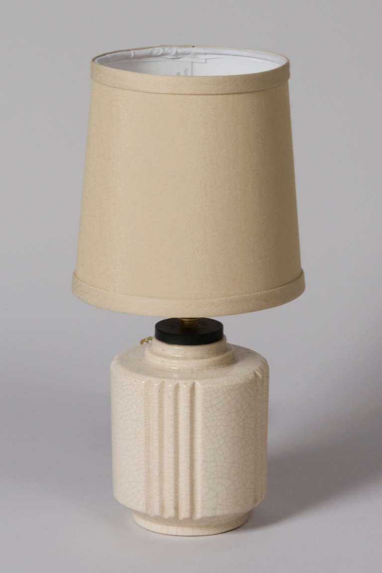 Crackle glaze cylindrical form ceramic lamp, in off white color, with deep grooves on sides, by Robert Lallemant, French 1930s. Overall height to top of shade 12 3/4 in, height of ceramic base 5 1/4 in, diameter of base 4 1/2 in, shade measures top