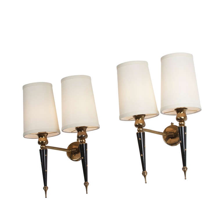 Pair of two arm wall sconces, black lacquered metal double posts joined by brass elements meeting at center circular backplate, the posts having small brass star decorations. In custom silk shades. French 1950s. Overall dimensions: height 16 in,