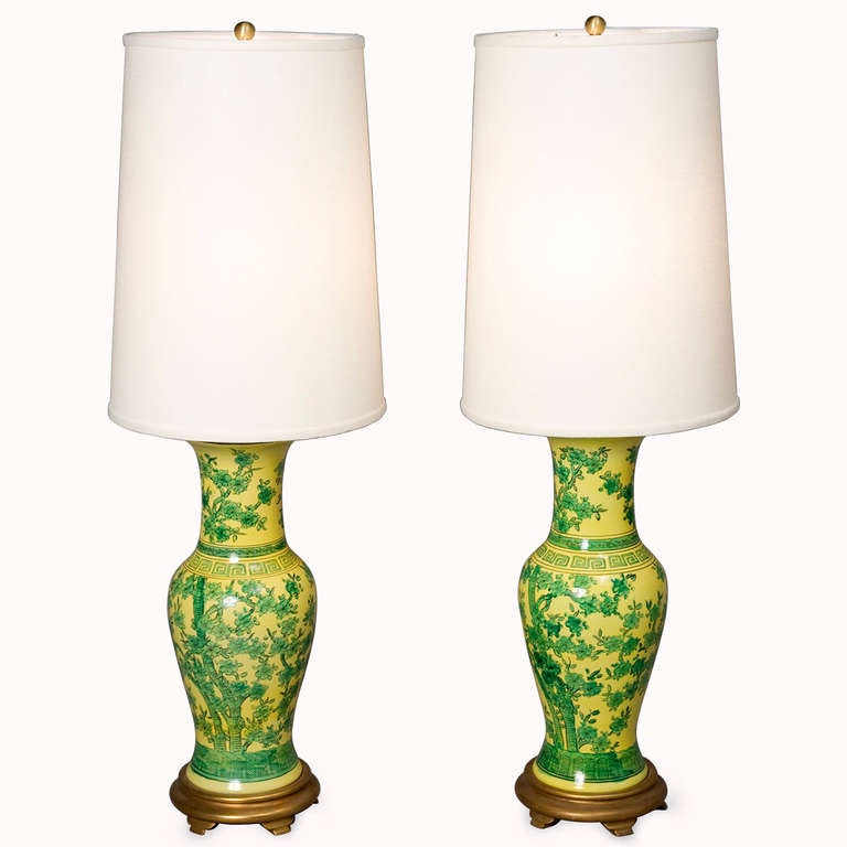 Pair of green flower decorated yellow base ceramic table lamps in urn form resting on a gilt wood base, in the Chinese style, with custom silk shades, each lamp having a double cluster, by Marbro, American 1960s. Overall height 38 1/2 in. Shade