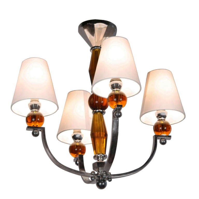 Four arm nickeled bronze chandelier, with amber glass central post, each arm terminating in a amber glass ball element, to which shade and socket are affixed, French, 1940s. Overall height 20 in, diameter including shades 20 in. (Item #1909)