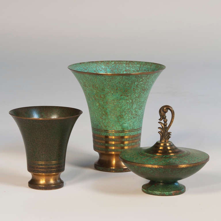 Three verdigris bronze objects, two trumpet form vases with bronze colored bands at bottom, one large and one small, and lidded dish with bronze decorative handle, by Carl Sorensen, American, circa 1920. Signed. Height of larger vase 7 1/2 in, top
