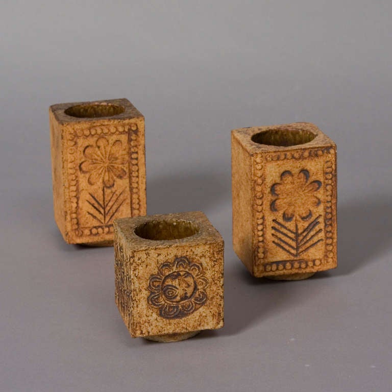 Set of three cube form ceramic pencil holders or small vases, with cylindrical interiors, the forms raised on small circular pedestal, with sun and flower decoration, by Roger Capron, French 1970s. The larger: 2 1/2 x 2 1/2 in square, height 4 1/16