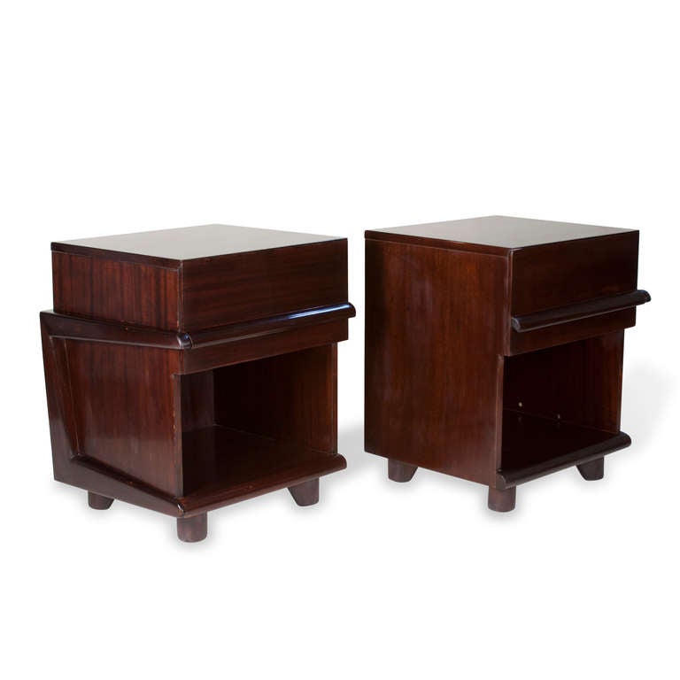 Pair of walnut end tables, upper drawer and open lower storage compartment, having molded element that crosses the front of drawer and wraps around to the side. Short wide circular legs. An opposing pair. American 1970s. Width 20 in, depth 18 in,