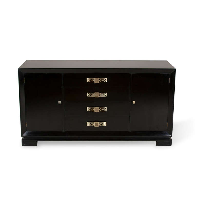 Black lacquer walnut credenza, four center drawers with decorative latticework bronze pulls, two side doors open to reveal an upper drawer and lower shelf and storage compartment, the body raised on two greek key shaped supports at either end.
