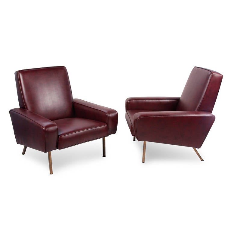 Pair of upholstered armchairs, the square arm body supported by tubular brass legs, by Pierre Guariche for Airborne, French, 1950s. Newly upholstered in high quality burgundy vinyl. Back height 32 in, width 31 in, depth 34 1/2 in. Price is for the