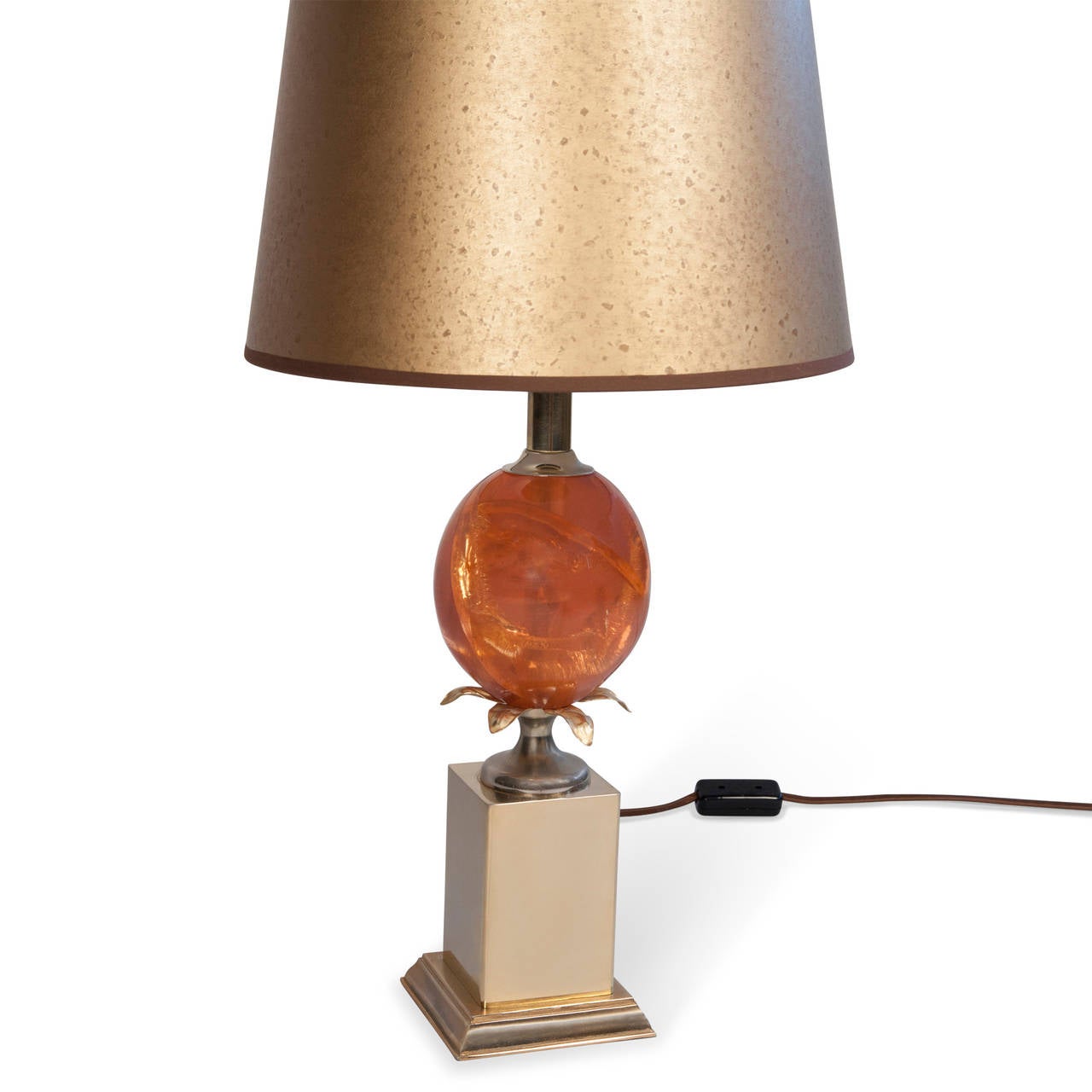 Single fractured resin table lamp, the orange resin in an ovoid shape, resting on a square brass base, French early 1970s. In custom mottled gold paper shade. Overall height 25 1/2 in. Base measures 5 in square. Shade measures top diameter 10 in,