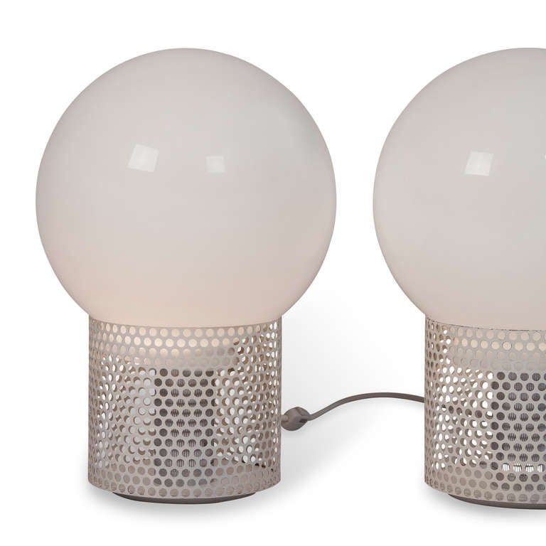 Pair of table lamps each composed of opaque glass sphere resting on a perforated off white enameled cylindrical base, by Michel Boyer for Rouve, French 1970.  Overall height 18 1/2 in, diameter of sphere 11 1/2 in, base has 8 in diameter and height