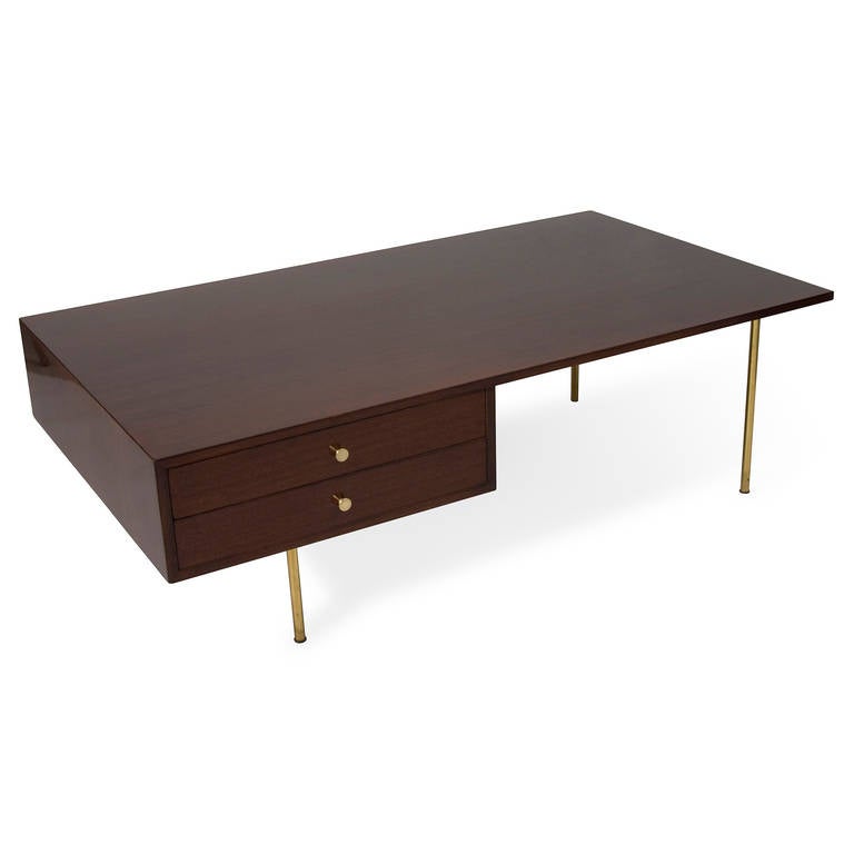 Solid mahogany rectangular coffee table, with two offset drawers having brass pulls, raised on four brass legs. Finished on all four sides. By Harvey Probber, American 1950s. 56 in x 32 in, height 18 in. (Item #1700)