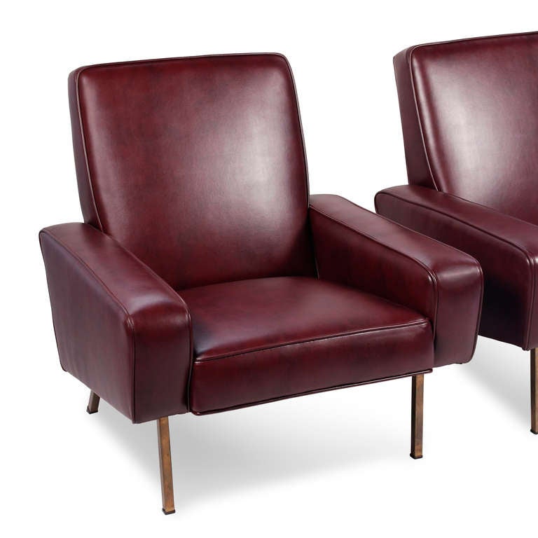 Pair of upholstered armchairs, the square arm body supported by tubular brass legs, by Pierre Guariche for Airborne, French 1950s. Newly upholstered in high quality burgundy vinyl.  

Back height 32 in, width 31 in, depth 34 1/2 in.