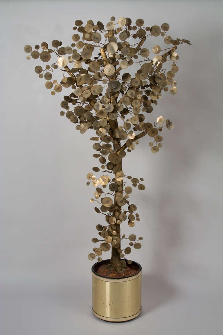 Large brass and gilt painted wood tree sculpture, the leaves in patinated brass discs, attached to genuine wood tree, the tree trunk set into resin filled circular gold color plastic pot, by C. Jere, America early 1970s. Height 74 in, width at
