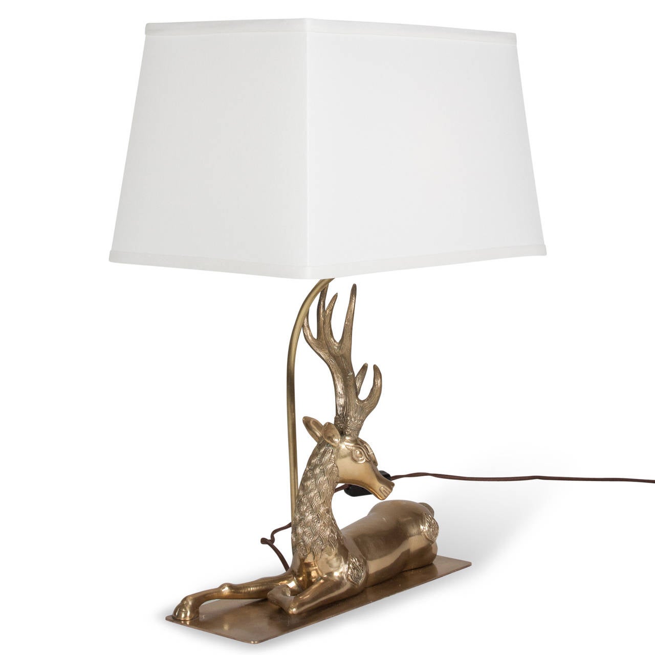 Antlered deer or elk sculptural table lamp, the animal resting on a rectangular sheet, French 1970s. In a custom linen shade. Overall height 22 1/2 in, base measures 13 3/4 in x 4 3/4 in. Shade measures at top 8 x 13 in, at bottom 10 x 15 in, height