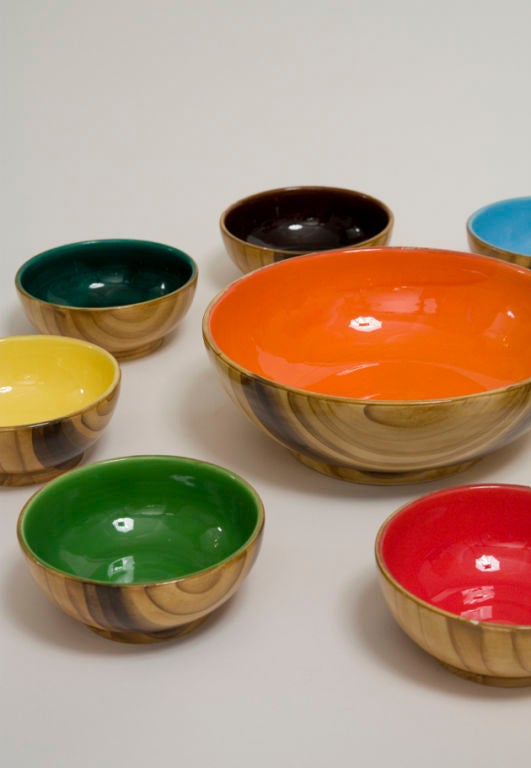 Nine piece ceramic salad service, the exterior of the bowls in a faux bois glaze, the interior in an assortment of bright colors. One serving bowl of diameter 8.5 in, and eight salad bowls of diameter 4.75 in. By Grandjean Jourdan, Vallauris, French