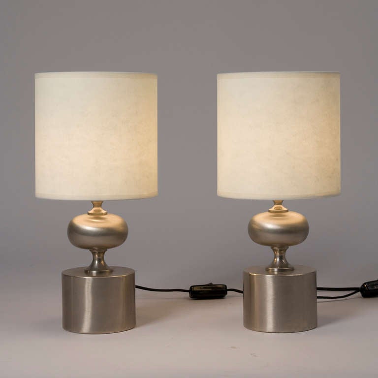 Pair of brushed stainless steel small table lamps, the base a spherical ovoid over a circular base, by Maison Barbier, French 1970s. In custom paper shades. Overall height 14 1/2 in, diameter of shade 7 1/4 in, diameter of base 4 1/4 in, height of