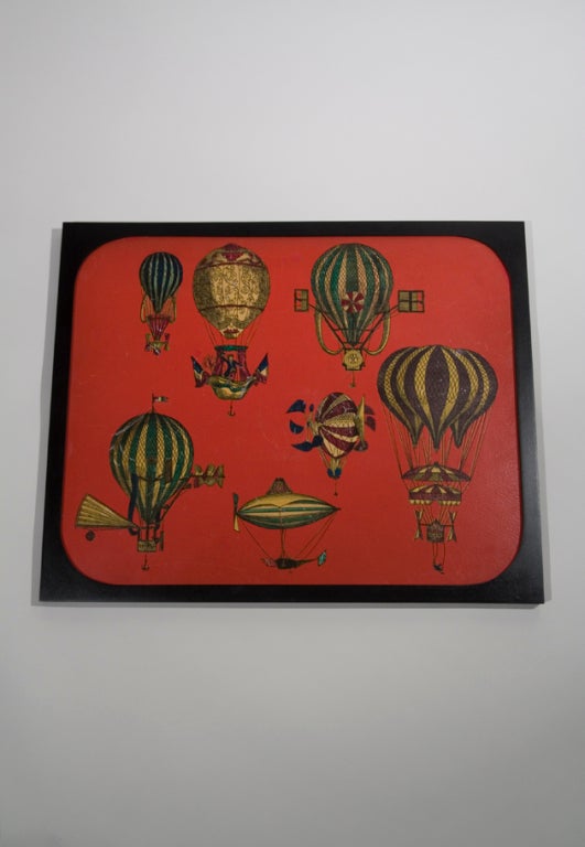 Lithograph panel, intended for use as an ink blotter, framed, the red ground with colorful hot air balloon decoration, by Piero Fornasetti, Italian 1950s. With original label to back. Panel measures 18 in. x 23 in., framed 24 1/4 in. x 19 3/4 in.