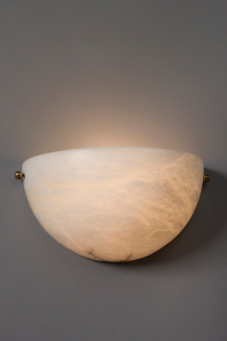 Pair of half-dome alabaster sconces, with small brass accent caps on either side, by Lightolier, American 1980s. Width 13 in, height 6 1/2 in, depth 7 in. 