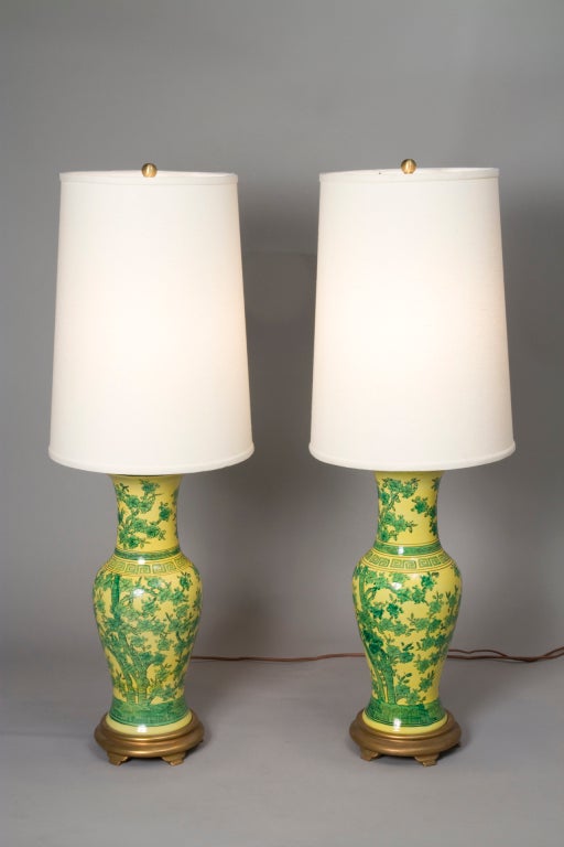 Pair of green flower decorated yellow base ceramic table lamps in urn form resting on a gilt wood base, in the Chinese style, with custom silk shades, each lamp having a double cluster, by Marbro, American 1960s. Overall height 38 1/2 in. Shade