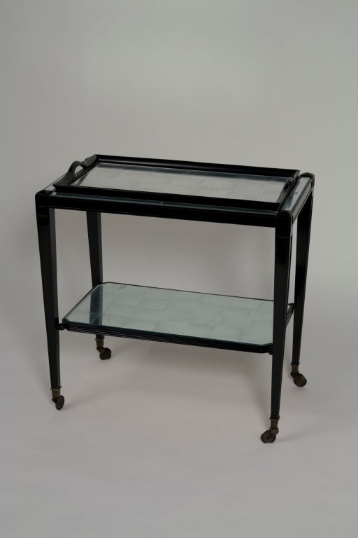 Two-tier black lacquer bar cart resting on four casters. Each surface is silver leafed under glass, the top surface holds a removable serving tray. French, 1940s. Height 24