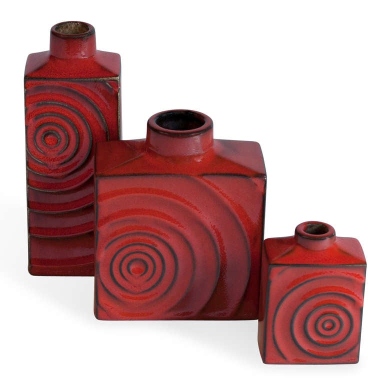 Set of three red glazed ceramic vases, of rectangular form with raised concentric circle decoration, 