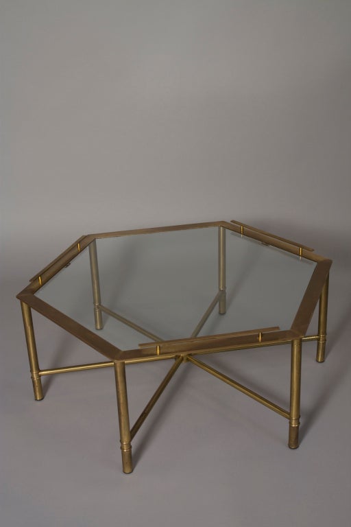 Bronze hexagonal shaped coffee table, with glass top, on six legs having stretchers meeting in center, and three of six sides of hexagon having raised gallery type edge, by Mastercraft, American 1970s. Distance from point to point 42 in, distance