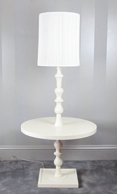 A hard-to-find lamp and table combination by the great Tommi Parzinger.  Turned wood column with round center table.  Piece has been enameled in a satin finish ivory enamel within the last 15 years.   Would be stunning lacquered in a color to your