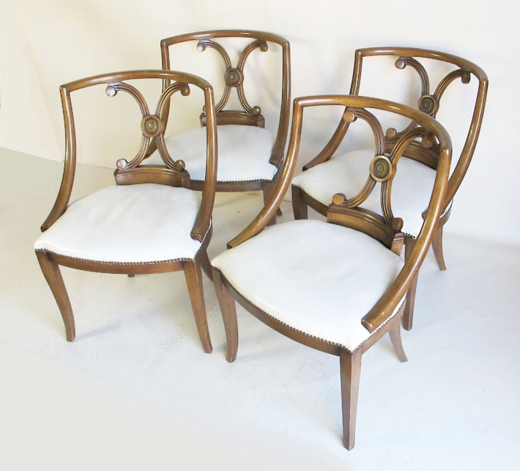 A very attractive set of four chairs in the Hollywood Regency style.  All original condition including white leather upholstered seats and brass nail heads.  These would be wonderful dining or sides chairs and could be pulled up to a game table.