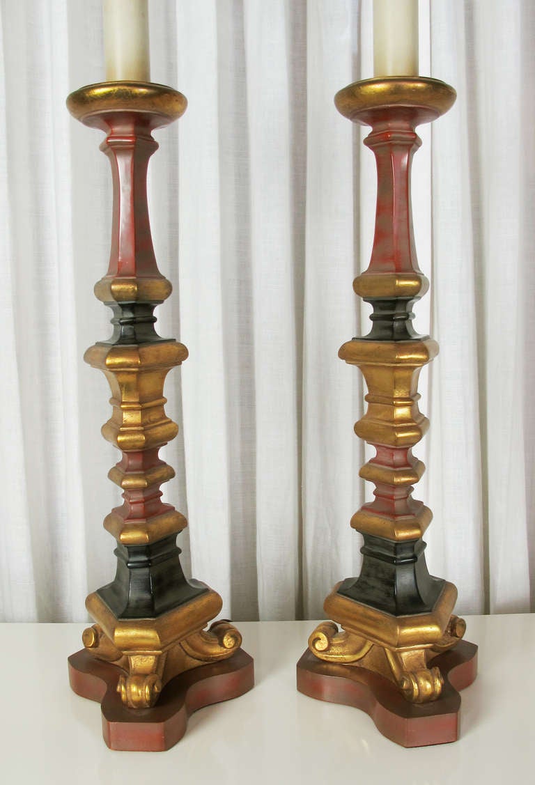 Here is a highly decorative pair of mid-century candlestick lamps in the Spanish Revival style.  Richly colored in a deep red and black with deep gold accents.  Lamps retain original finials.  Shades not included.