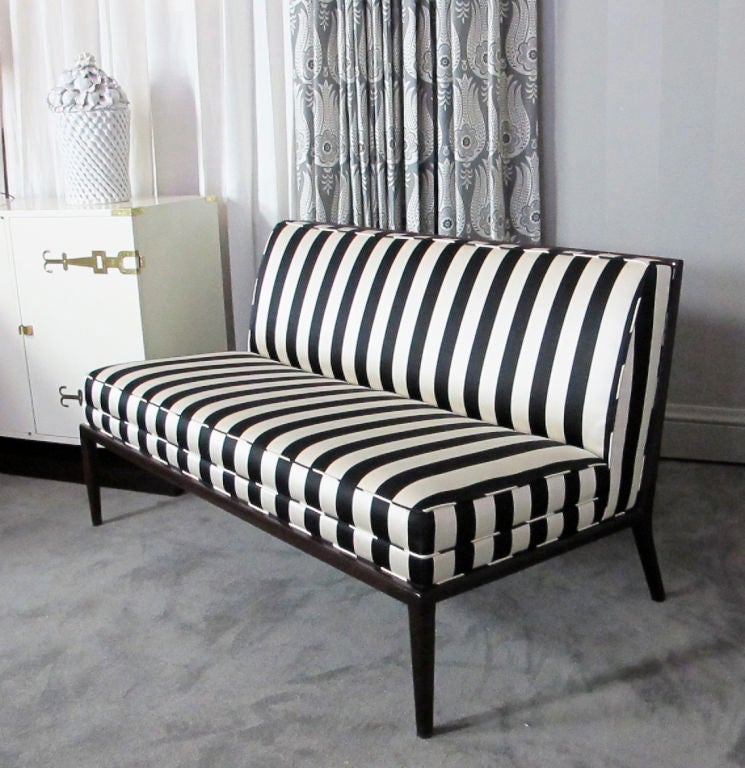 This is an elegant tight-back armless settee or bench attributed to T.H. Robsjohn-Gibbings for Widdicomb.   The mahogany frame subtly curves to support the back of the settee.  Beautifully reupholstered in black and ivory silk.  Base refinished.