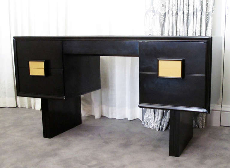 This is a very handsome ebonized wood and yellow leather knee hole desk attributed to California designer, Paul Laszlo.  The desk consists of a single center drawer flanked by two drawers on one side and a hinged door on the other.  Square pulls and