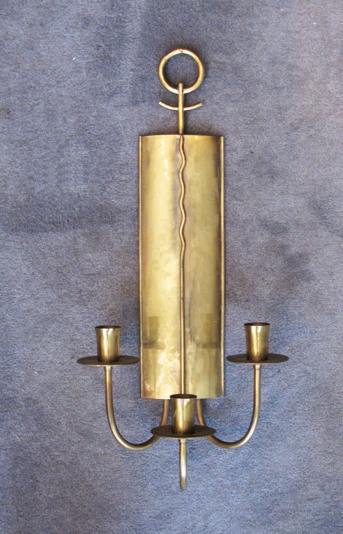 A handcrafted pair of three-arm candle sconces by Grag Studios. Hans Grag immigrated to the United States from Germany in the late 1920's. Evidence of his German training can be seen in design details, with similarities to the work of Tommi