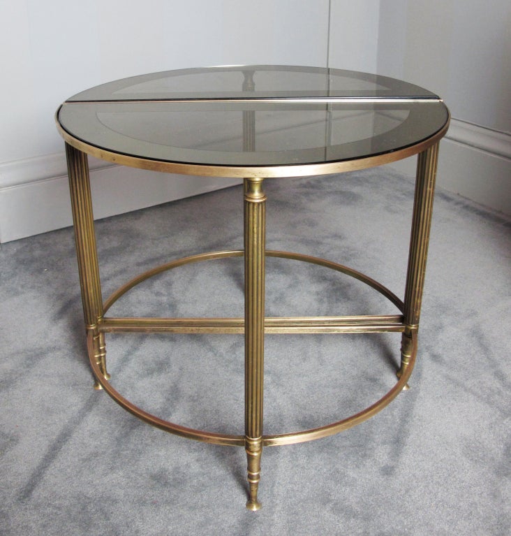 A very elegant pair of demi lune brass tables in the style of Maison Jansen.  The pair of tables can be used separately, or can be used together to form round cocktail or side table.  Tables retain original glass tops with mirror border.  Dimensions